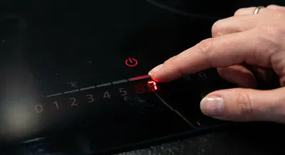 Main réglant le thermostat d'une plaque à induction moderne