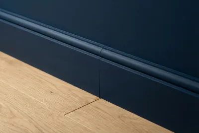 Gros plan sur une plinthe bleu marine peinte de la même couleur que le mur sur parquet