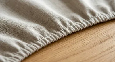Gros plan sur l'ourlet élastique d'une nappe moderne sur une table en bois.
