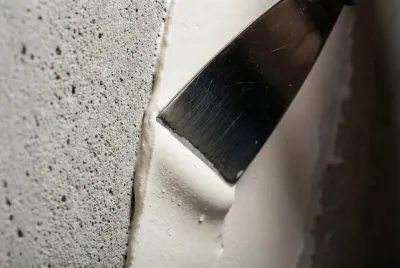 Gros plan sur l'application d'un enduit de lissage sur un mur à relief