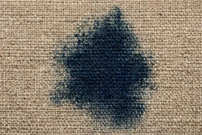 Gros plan macro montrant le transfert de couleur bleu jean sur un tissu d'ameublement clair.