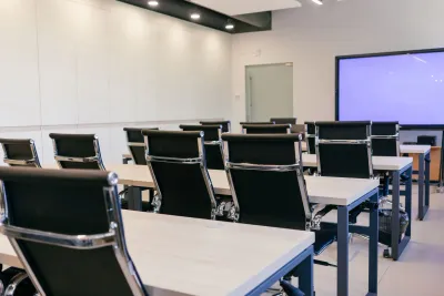 Salle de conférence spacieuse et moderne avec des chaises noires et un écran de projection.