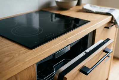 Gros plan sur une plaque à induction avec lave-vaisselle entrouvert en dessous