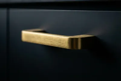 Gros plan contrasté sur une poignée de meuble de cuisine en métal brossé