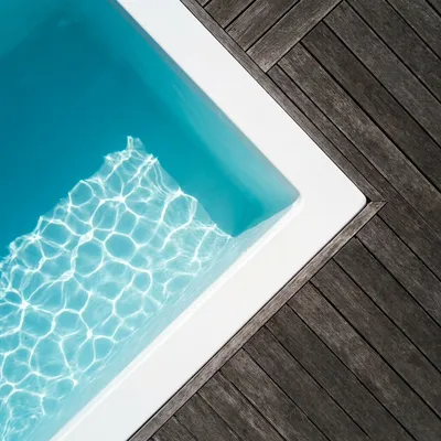 Détail minimaliste d'une piscine coque avec eau cristalline et terrasse en bois