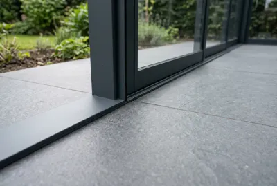 Gros plan sur la jonction entre le bas de la véranda en aluminium et le carrelage de la terrasse